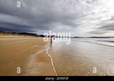 Frau zu Fuß entlang der wunderschönen Camusdarach Strand in den schottischen Highlands in der Nähe von Fort William und Mallaig Stockfoto