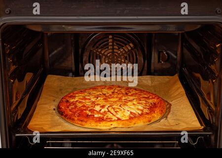 Nahaufnahme hausgemachte Pizza mit Hühnerfleisch, Paprika, Tomaten und Käse im heimischen Ofen. Geringer Fokus. Stockfoto