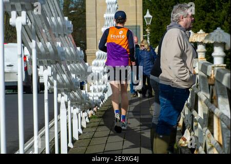 Marlow, Buckinghamshire, Großbritannien. 6th. Februar 2021. Ein Jogger ignoriert soziale Distanzierung, als er die Marlow Bridge überquert. Marlow in Buckinghamshire war heute trotz der nationalen Sperre sehr beschäftigt. Es gab Schlangen vor den Cafés und der Bauernmarkt war so hektisch wie jeder normale Samstag. Viele Menschen ignorierten heute die soziale Distanzierung, obwohl einige Gesichtsmasken trugen. Quelle: Maureen McLean/Alamy Live News Stockfoto