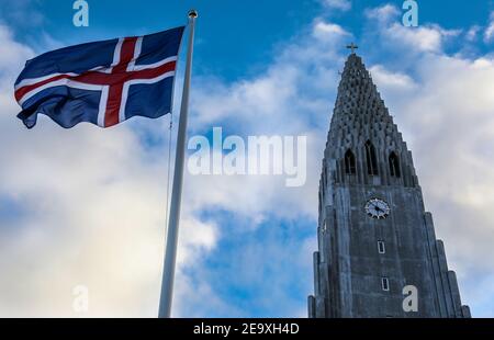 Die isländische Nationalflagge, die vor Hallgrímskirkja (Kirche von Hallgrímur) in Reykjavik, Island, fliegt Stockfoto