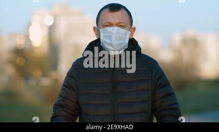 Porträt eines jungen Mannes im Freien in einem Einweg-Arzt Maske Stockfoto