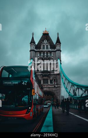 London UK Januar 2021 Vertikale Aufnahme der Tower Bridge während der nationalen Lockdown der britischen Regierung. Roter Doppeldeckerbus, der an der Brücke vorbeifährt Stockfoto