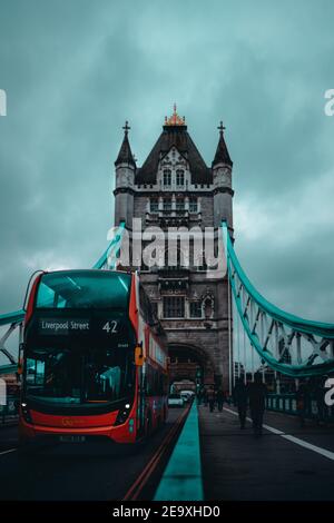 London UK Januar 2021 Vertikale Aufnahme der Tower Bridge während der nationalen Lockdown der britischen Regierung. Roter Doppeldeckerbus, der an der Brücke vorbeifährt Stockfoto