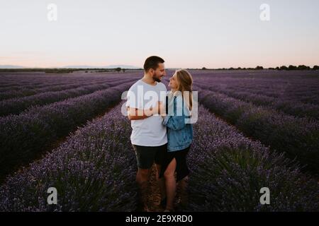 Inhalt Paar in der Liebe stehen in blühenden Lavendel Feld an Sonnenuntergang, während man sich umarmt und anschaut Stockfoto