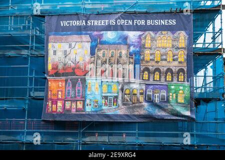 Edinburgh, Schottland, Großbritannien. 6. Februar 2021. Die Altstadt von Edinburgh ist fast verlassen an einem Samstagnachmittag während der nationalen Covid-19 Sperre. Alle nicht notwendigen Geschäfte, einschließlich aller touristischen Souvenirläden, sind geschlossen, ebenso Restaurants und Cafés. PIC; Banner auf Gerüst auf Victoria Street ist zu optimistisch. Iain Masterton/Alamy Live News Stockfoto