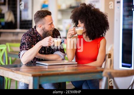 Ein zufriedenes multiethnisches Paar, das im Café sitzt und Zeit zusammen verbringt Während Sie das Wochenende genießen und sich gegenseitig betrachten Stockfoto
