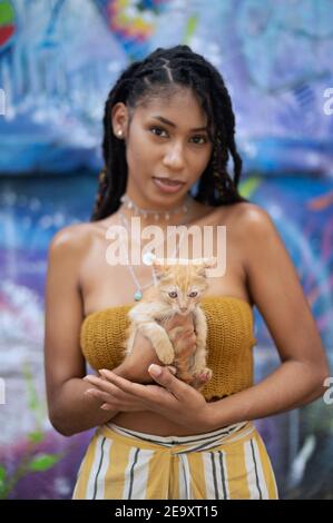 Außenportrait einer attraktiven jungen lateinischen Frau mit niedlichem Kätzchen in den Händen Stockfoto