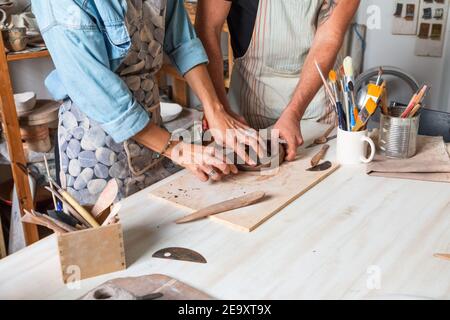 Cropped unkenntlich weiblich und männlich in legerer Kleidung und Schürzen Lächelnd während des Töpferunterlassenunterlassens in der Werkstatt Stockfoto