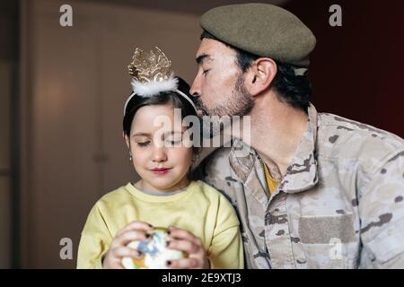 Bärtiger Mann in Militäruniform küssen kleine Mädchen während sitzen Schließen Sie, bevor Sie das Land bedienen Stockfoto