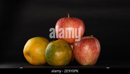 Äpfel und Orangen auf schwarzem Hintergrund angeordnet Stockfoto