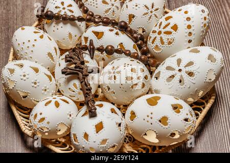 Frohe Ostern.Weiße Hand gemacht Ostereier mit Kruzifix in Holzkorb.Frühling Dekoration Hintergrund. Festliche Tradition für die osteuropäischen Länder Stockfoto