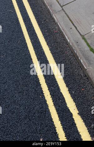 Frisch gestrichene doppelte gelbe Linien auf einer asphaltierten Straße Stockfoto