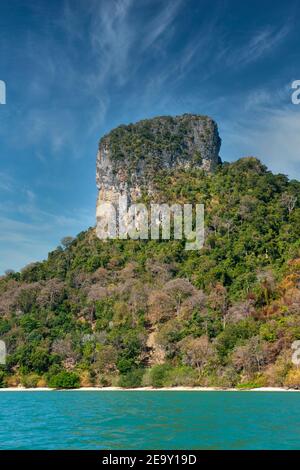 Eine riesige Felsformation überschattet den weißen Sand und das blaue Meer des Railay Beach in Krabi, Thailand Stockfoto