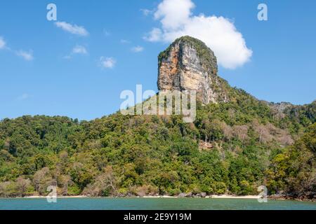 Eine riesige Felsformation überschattet den weißen Sand und das blaue Meer des Railay Beach in Krabi, Thailand Stockfoto