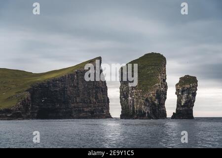 Nahaufnahme der berühmten Drangarnitr Klippe mit den Tindholmur Inseln in Der Hintergrund wurde während der morgendlichen Wanderung im Frühjahr aufgenommen Färöische Küste Stockfoto