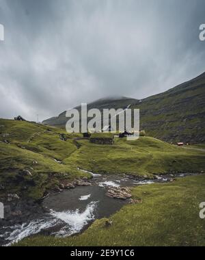 Wasserfälle in der Ortschaft Saksun auf den Färöer Inseln. Keine Menschen um, traditionelle Häuser aus Stein. Stockfoto