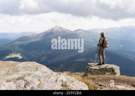 Frau wandern mit Rucksack und Wanderstöcken am Sommertag. Naturtourismus in ukrainischen Karpaten Berge. Stockfoto