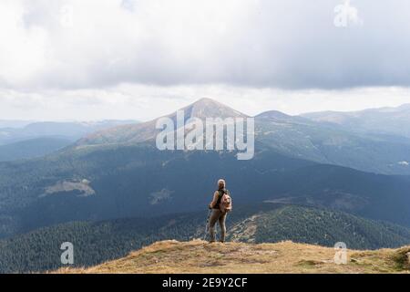 Frau wandern mit Rucksack und Wanderstöcken am Sommertag. Naturtourismus in ukrainischen Karpaten Berge. Stockfoto