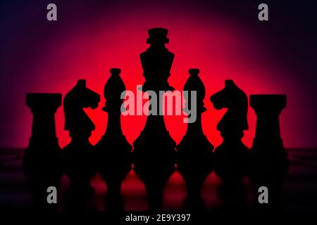Silhouetten Schachfiguren vor einem dunkelroten und schwarzen Hintergrund, King, Bishop, Horse und Rock. Stockfoto