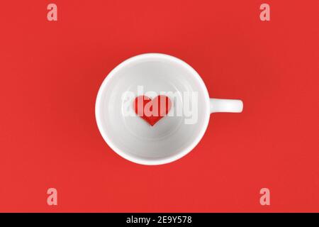 Teetasse mit Herz innen auf rotem Hintergrund Stockfoto