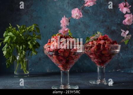 Vinegret oder Vinaigrette. Traditioneller russischer roter Salat mit gekochtem und eingelegtem Gemüse, Erbsen, Rote Bete, in zwei Glasschüsseln auf grauem Hintergrund. Stockfoto