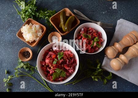 Vinegret oder Vinaigrette. Traditioneller russischer roter Salat mit gekochtem und eingelegtem Gemüse, Erbsen, Rote Bete, in weißer Schüssel auf grauem Hintergrund. Stockfoto