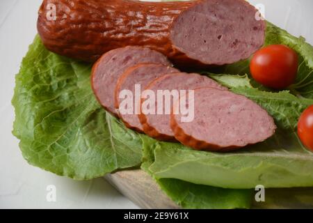 In Scheiben geschnittenes, würziges Rind-/Schweinewurst.mit Salatblatt und Kirschtomaten. Stockfoto