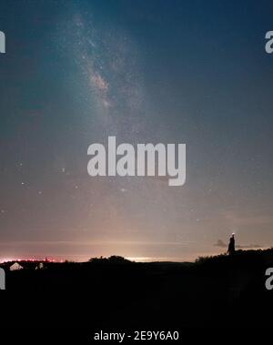 Mann hält eine Taschenlampe hoch und beleuchtet die Nacht Himmel mit der Milchstraße im Hintergrund Stockfoto