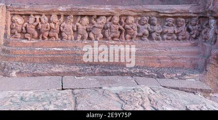 Badami, Karnataka, Indien - 7. November 2013: Höhlentempel über dem Agasthya See. Nahaufnahme der restone Skulptur der Reihe der kleinen menschlichen Figuren tanzen und Stockfoto