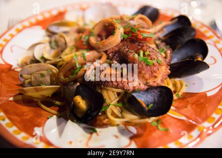 Italienische Küche: Spaghetti mit Meeresfrüchten mit gegrilltem Oktopus und Muscheln auf einer handbemalten Keramikplatte der Insel Capri, Tyrrhenisches Meer, Italien Stockfoto