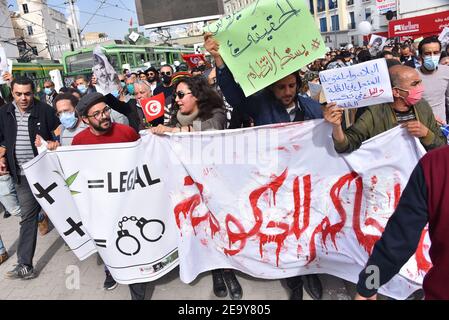 Demonstranten marschieren mit einem riesigen Banner, das ihre Meinung zum Ausdruck bringt, während einer Demonstration gegen die Repression von Regierung und Polizei, während sie des 8th. Jahrestages der Ermordung des prominenten linken Oppositionsführers Chokri Belaid gedenken. Stockfoto
