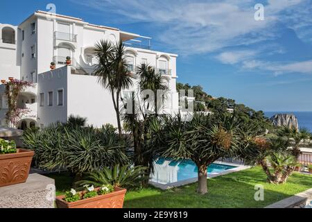 Insel Capri, Tyrrhenisches Meer, Italien - Mai 18 2016: Blick auf einen Hotelgarten mit Pool und Faraglioni-Lifs im Hintergrund. Stockfoto