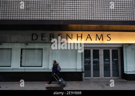 Eine Person geht an geschlossenen Türen und leeren Schaufenstern im geschlossenen Debenhams-Laden in der Oxford Street in London vorbei. Arbeiter wurden gesehen, wie sie am Samstag im ehemaligen Flagshipstore Armaturen und Armaturen ausbauten. Bilddatum: Samstag, 6. Februar 2021. Stockfoto