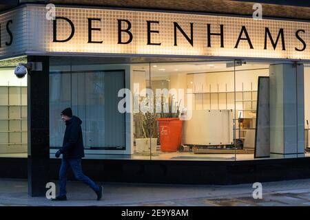 Eine Person geht an geschlossenen Türen und leeren Schaufenstern im geschlossenen Debenhams-Laden in der Oxford Street in London vorbei. Arbeiter wurden gesehen, wie sie am Samstag im ehemaligen Flagshipstore Armaturen und Armaturen ausbauten. Bilddatum: Samstag, 6. Februar 2021. Stockfoto