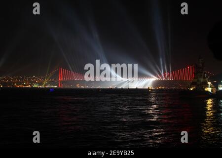 Feuerwerk über dem Istanbuler Bosporus während der Feierlichkeiten zum Tag der Türkischen Republik. Bosporus-Brücke mit roter Beleuchtung und Lasern bei Nacht. Stockfoto