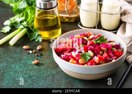 Konzept der traditionellen russischen Küche. Rote Beete Salat Vinaigrette mit eingelegten Gurken, Bohnen, Karotten, Erbsen, Sauerkraut auf einer dunklen Arbeitsplatte. SPA kopieren Stockfoto