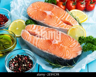 Zwei rohe frische Steak Fisch Forelle, Lachs und Gewürze auf einem blauen Holzhintergrund Stockfoto