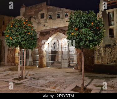 Ruinen des jüdischen antiken Viertels in der Altstadt von Tarragona. Spitzbögen aus der archäologischen Ausgrabung enthüllt, Orangenbäume vor der Stockfoto