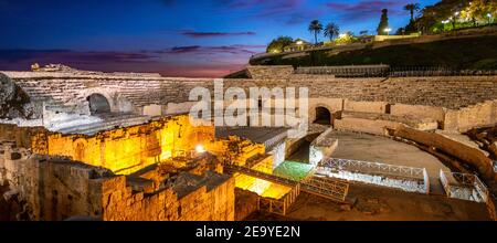 Ruinen des antiken römischen Amphitheaters bei Nacht, Gebäude beleuchtet bei Sonnenuntergang, blau und rosa Himmel, romanische Kirche in der Arena Amphitheater. Cit Stockfoto