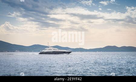 Luxus große Yacht segelt auf der Adria bei Sonnenuntergang. Küstenlinie mit Bergkette von Zadar Bucht, Kroatien gesehen Stockfoto