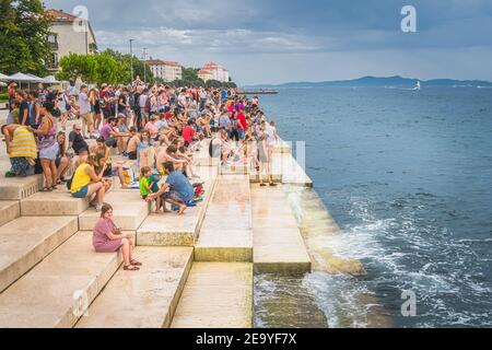 Zadar, Kroatien, Juli 2019 die Menge der Touristen hören Meeresorgel, Morske orgulje, Sound Art Objekt, das Musik über Meereswellen und Röhren spielt Stockfoto