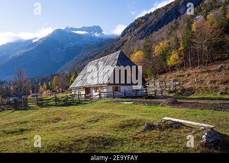 Traditionelles Trenta Haus in den Julischen Alpen mit einem Holzdach und einem alten Holzzaun, der das Haus umgibt. Stockfoto