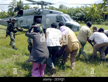 Indonesische Zivilisten stürzen sich, um ihre Verletzten in einen SH-60B Seahawk-Hubschrauber zu laden, der den Saberhawks of Anti-Submarine Squadron Light Four Seven (HSL-47) während einer humanitären Hilfsamission nach Aceh, Sumatra, Indonesien, zugewiesen wurde. Hubschrauber und Flugzeuge, die Carrier Air Wing Two (CVW-2) und Matrosen aus Lincoln zugewiesen sind, führen humanitäre Operationen im Gefolge des Tsunamis durch, der Südostasien heimsuchte. Foto von Tyler J. Clements/USN via ABACA Stockfoto