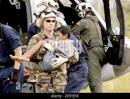 LT. Shawn Harris, der dem Lenkflugkörper-Zerstörer USS Shoup (DDG 86) zugeordnet ist, bringt einen verletzten Jungen von einem MH-60s Knighthawk Hubschrauber zu einem Triage-Standort, der von verschiedenen Hilfsorganisationen auf der Sultan Iskandar Muda Air Force Base in Aceh, Sumatra, eingerichtet wurde. Medizinische Teams der USS Abraham Lincoln (CVN 72) Carrier Strike Group, Carrier Air Wing Two (CVW-2) und der International Organization for Migration (IOM) haben eine Triage-Site auf der Sultan Iskandar Muda Air Force Base in Banda Aceh, Sumatra, eingerichtet. Die beiden Teams arbeiteten mit Mitgliedern der australischen Luftwaffe zusammen, um ein medizinisches Erstfahrzeug zu liefern Stockfoto