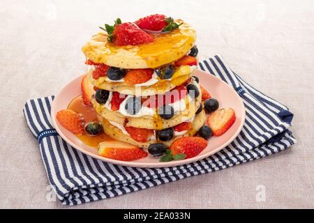 Pfannkuchen mit frischer Sahne, Erdbeeren, Heidelbeeren und Ahornsirup Stockfoto