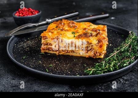 Lasagne mit Hackfleisch Rindfleisch und Tomate Bolognese Sauce auf einem Teller. Schwarzer Hintergrund. Draufsicht Stockfoto