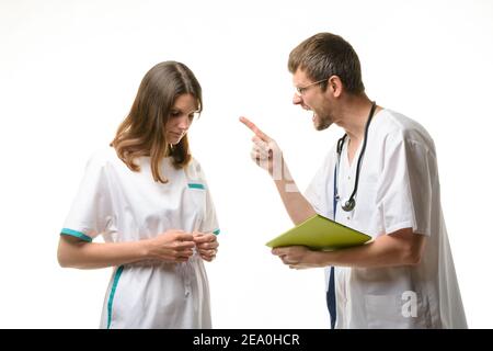 Der Arzt schreit beim Praktikanten nach einem Fehler in Der Patientendatensatz Stockfoto