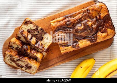 Hausgemachte Schokolade Bananenbrot auf einem rustikalen Holzbrett, Draufsicht. Flachlage, über Kopf, von oben. Stockfoto