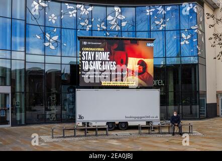 Beleuchtetes Tafelschild mit COVID-19 Lockdown "zu Hause leben zu retten"-Nachricht in Jubilee Square, Woking Stadtzentrum, Surrey, Südostengland Stockfoto