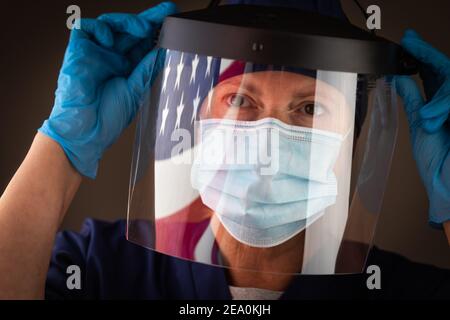 Amerikanische Flagge, die auf weibliche medizinische Arbeiterin mit Schutzmaske und Schild reflektiert. Stockfoto